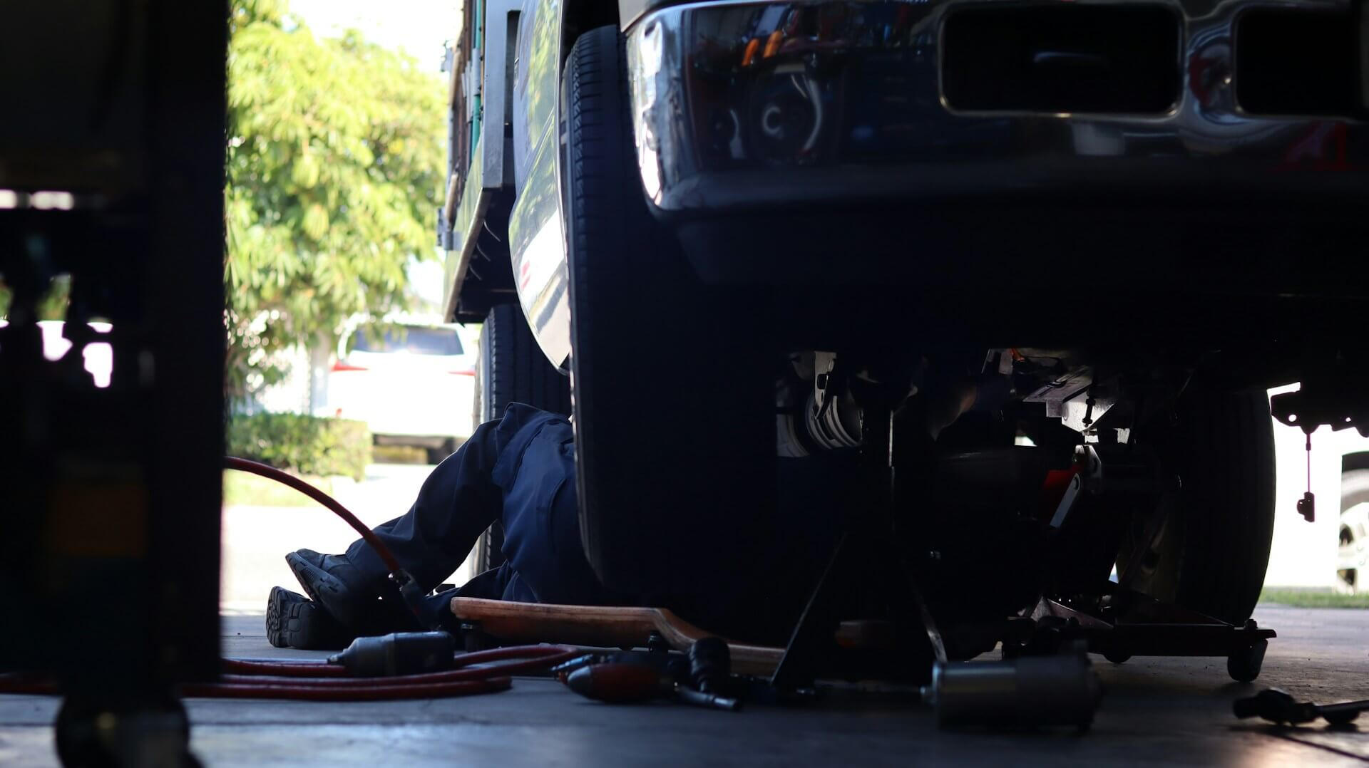 Mechanic performing mobile underbody car repair on a customer’s driveway in Windsor – Maxamy Mechanic underneath a car on a residential driveway with tools laid out, representing Maxamy’s convenient mobile mechanic service in Windsor and surrounding towns.