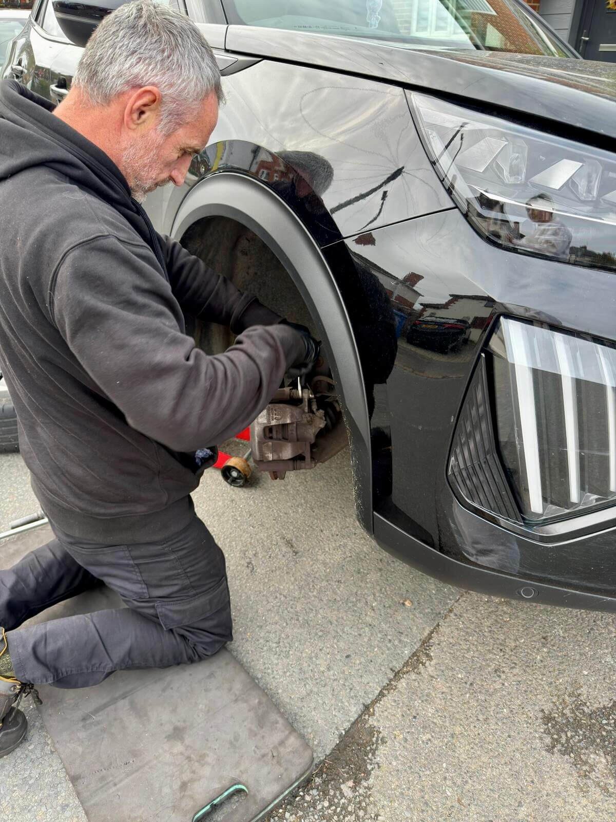 Brake calliper repair at your home Mechanic repairing a brake calliper on a black SUV during a mobile driveway repair in Beaconsfield.