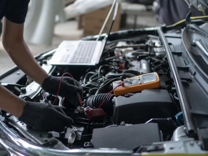 Mechanic performing diagnostic scan using a laptop and multimeter on a car in Bracknell, Beaconsfield or similar areas.