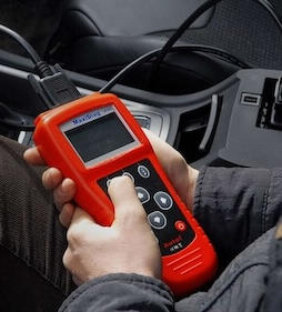 Running an OBD diagnostic scan inside the vehicle Close-up of a mechanic using a handheld OBD scanner inside a car to read diagnostic fault codes.